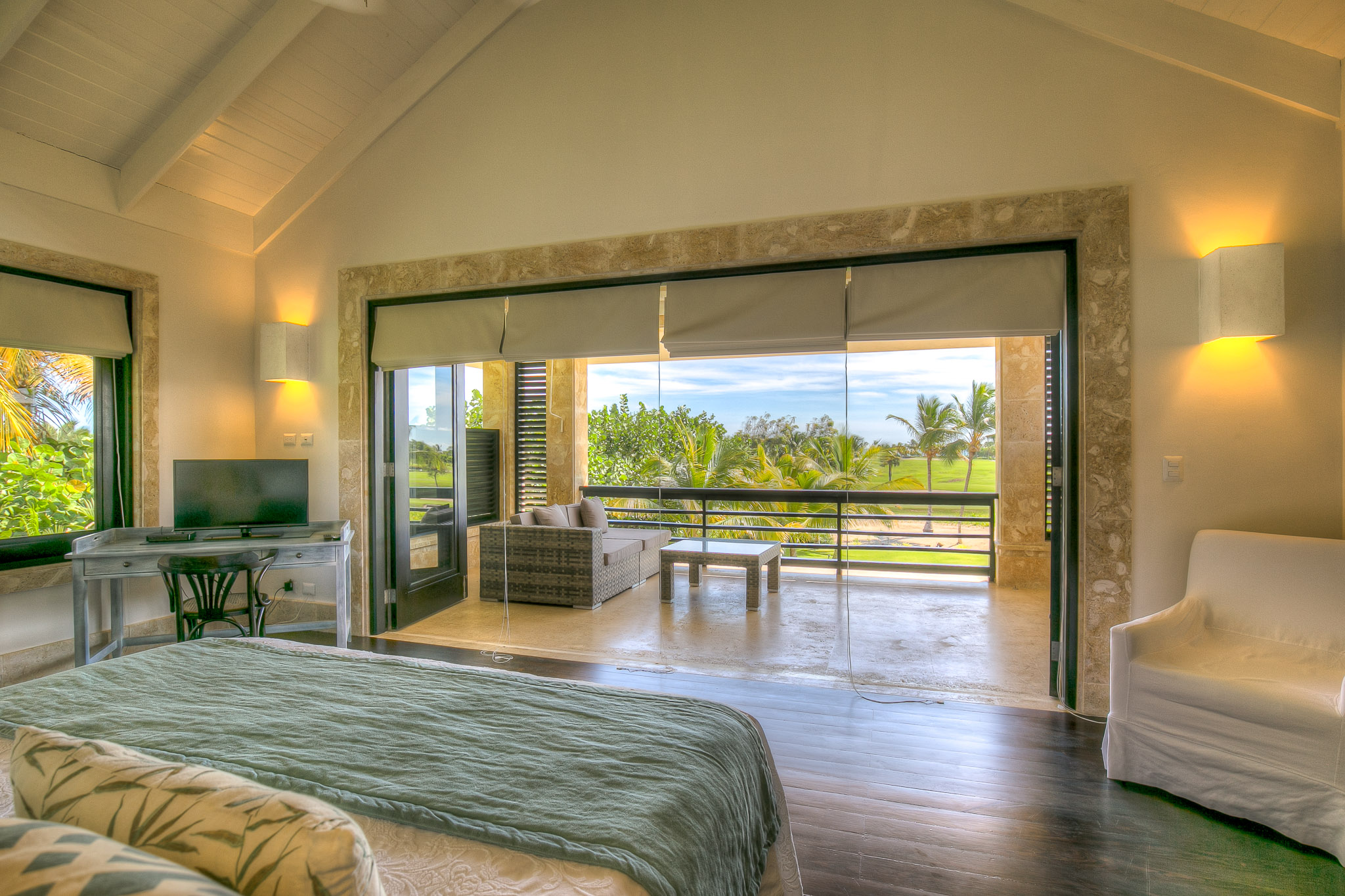 Bedroom at Casa de las Meninas with pale stone surrounds and a balcony overlooking palms and green landscape