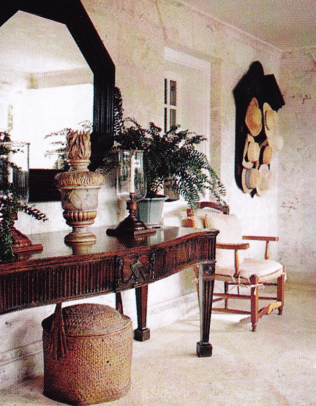 First-floor loggia with a carved dark wood table, plants, a mirror and woven basket