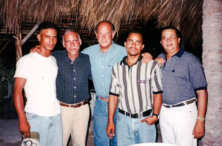 Five men in a family photograph; Miguel H. Peña identifies Oscar de la Renta at center, Ernesto Buch immediately to his left in the image, Miguel A. Peña at far right, and two workers